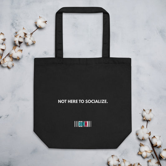 Black organic cotton tote bag with the text “NOT HERE TO SOCIALIZE.” in a minimalist white print, Gen X anti-social design.
